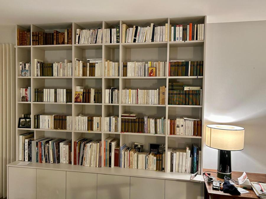 Bibliothèque occupant un mur, avec niches ouvertes et rangements bas